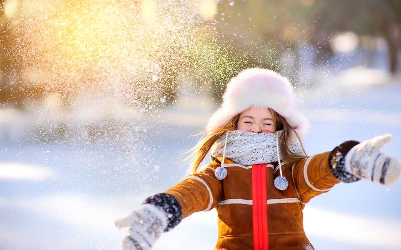 Little girl playing in the snow during the holiday season - contact Romp n' Roll for holiday learning!