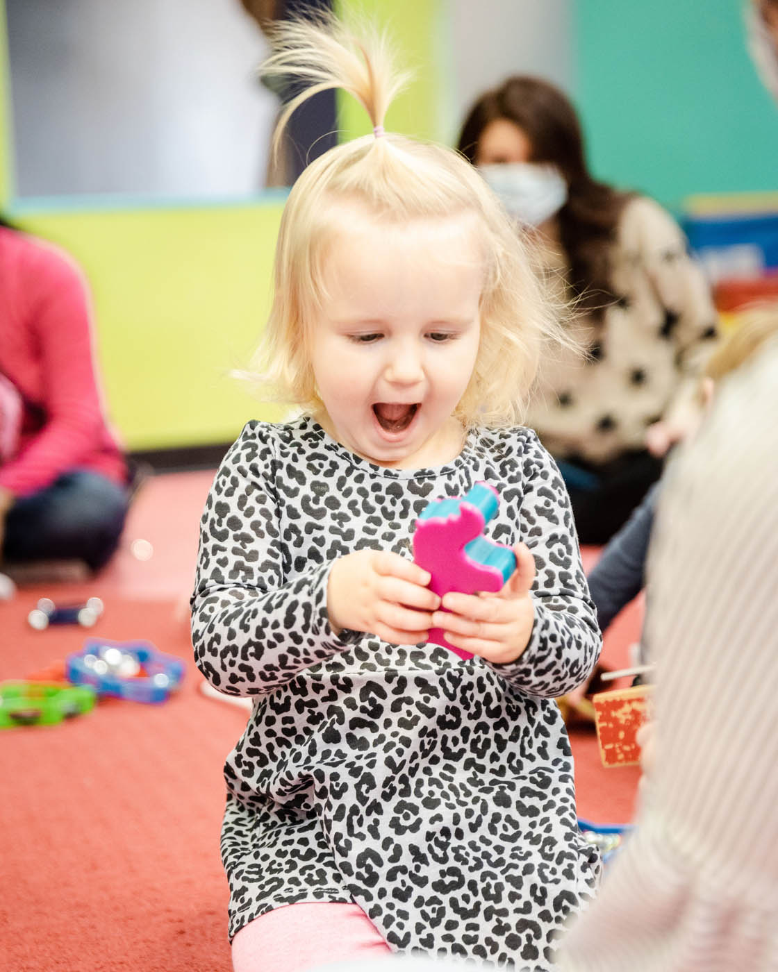 A little girl playing with a fuzzy ball at Romp n' Roll's playgroup.