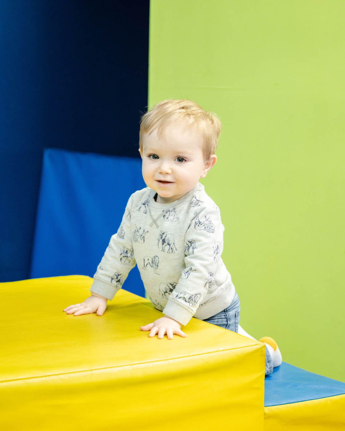 A young boy climbing on some age appropriate gym equipment at Romp n' Roll's toddler tumbling class.