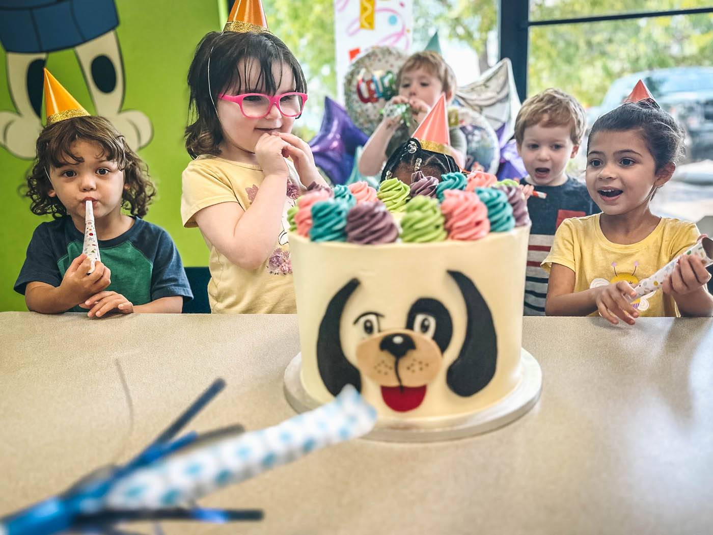 A young girl celebrating her birthday with friends and a Rompy cake at Romp n' Roll toddler birthday venues.