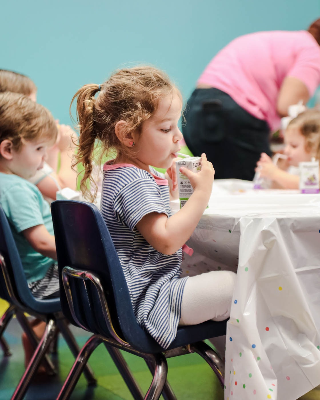 A littel girl sipping from a juice box at Romp n' Roll's birthday party.