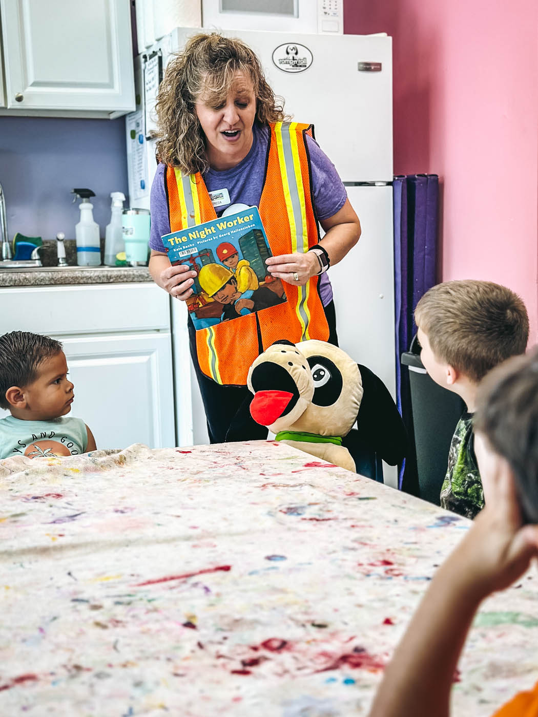 An instructor at Romp n' Roll with a group of kids - learning and reading a story together.