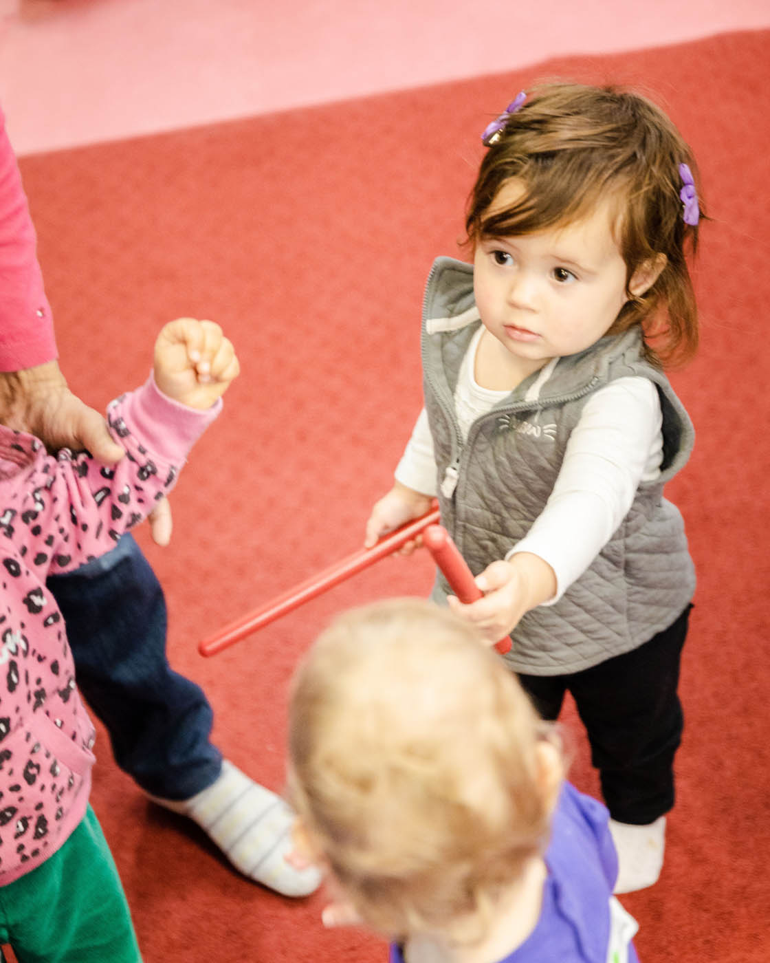 A little girl holding musical instrument ready to play at Romp n' Roll.
